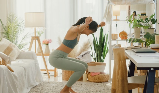Young Asian athletic woman sitting on scales and excited over result of her weight loss diet in living room at home. Diet and healthy weight loss.