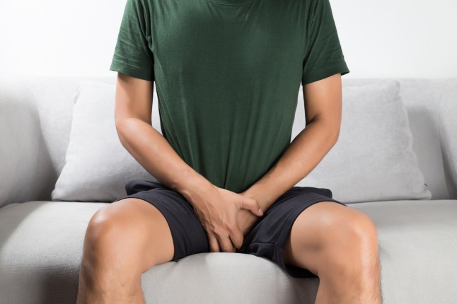 Asian man wants to pee and is holding his bladder.