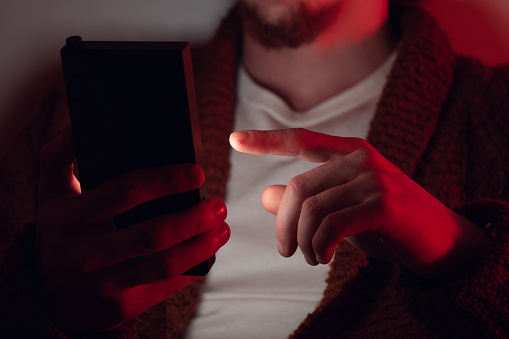 A mobile phone in the hands of a man. A young guy is holding a phone in his hands. The fraudster sends an email message. I work as a freelancer, a businessman. The husband checks messages and notifications on social networks. Wireless technologies.