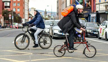 Two cyclists cross paths in Dublin, Ireland.
