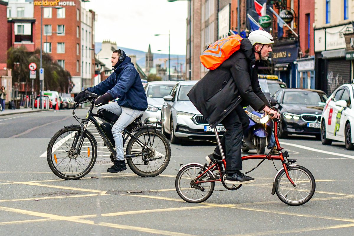 Two cyclists cross paths in Dublin, Ireland.