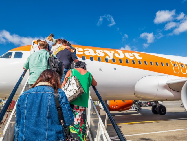 Passengers climbing steps to board an easyJet plane at the airport.