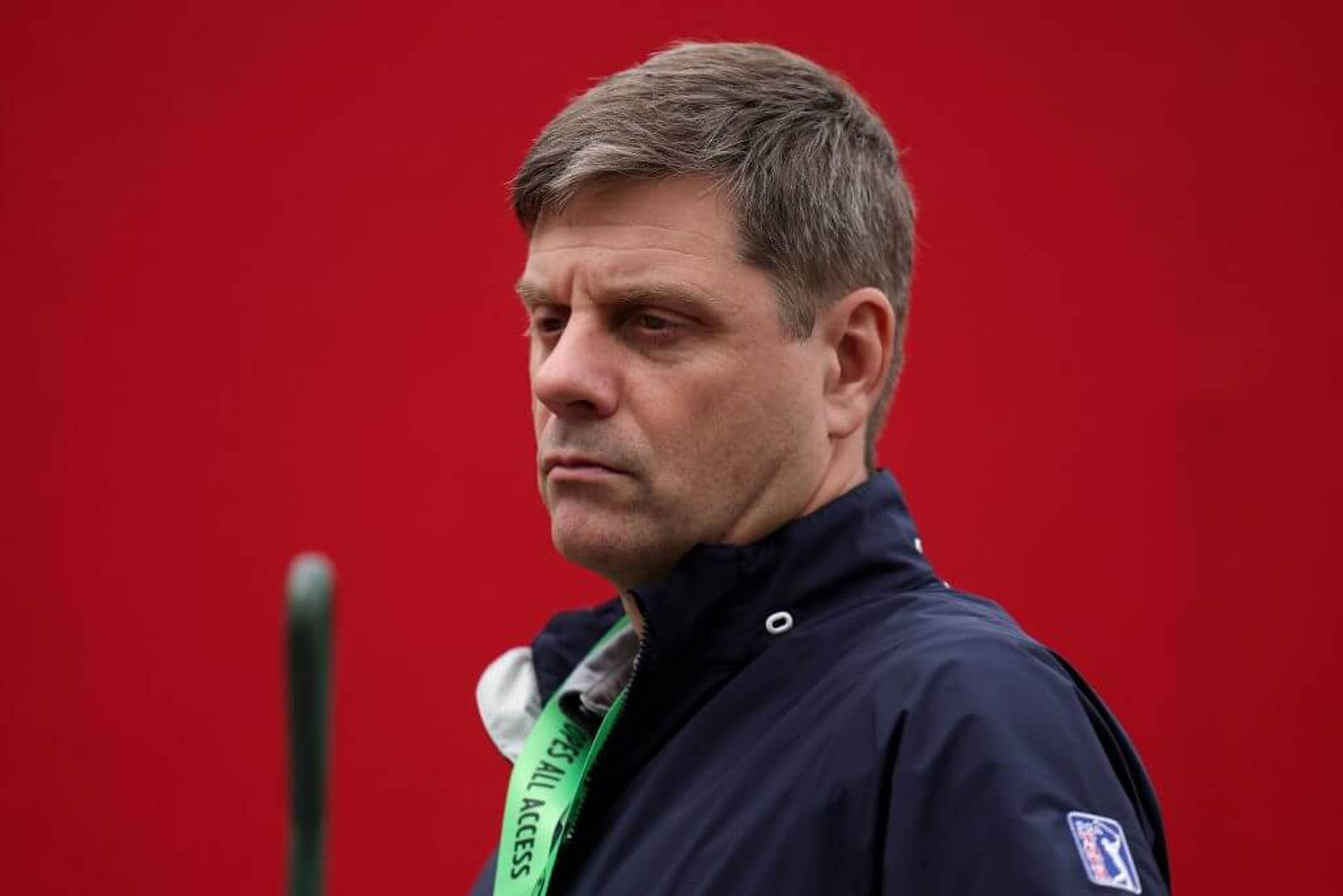 PGA Tour CEO Brian Rolapp stands in front of a red background and looks on prior to the Ryder Cup 2025 in Farmingdale, N.Y.