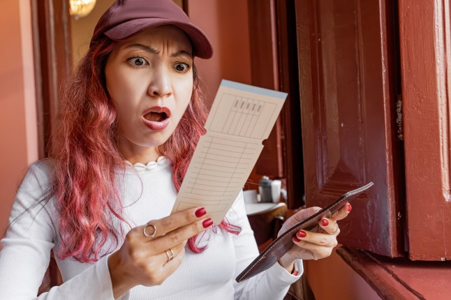 Woman with a shocked expression, holding a restaurant bill