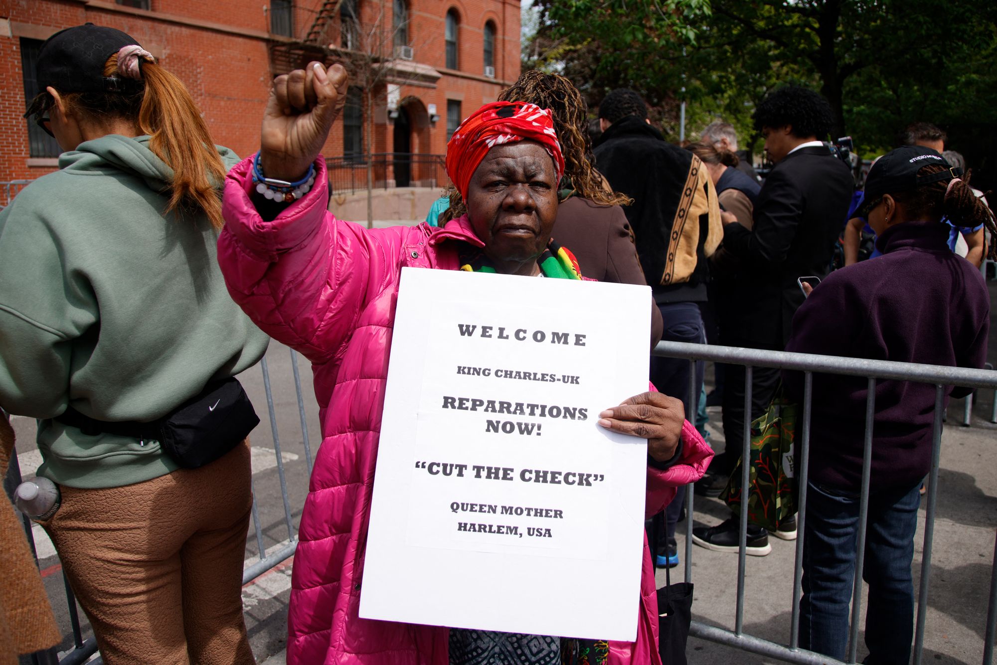 A woman holds a sign ahead of a visit by Britain's King Charles III to the non-profit Harlem Grown in New York