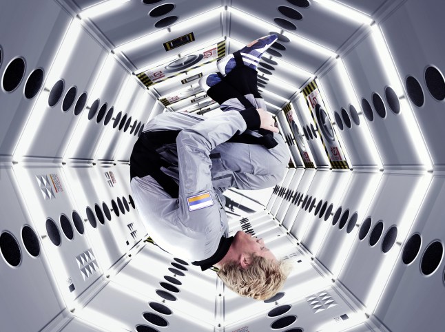 Male astronaut floating upside down in space station (Composite)