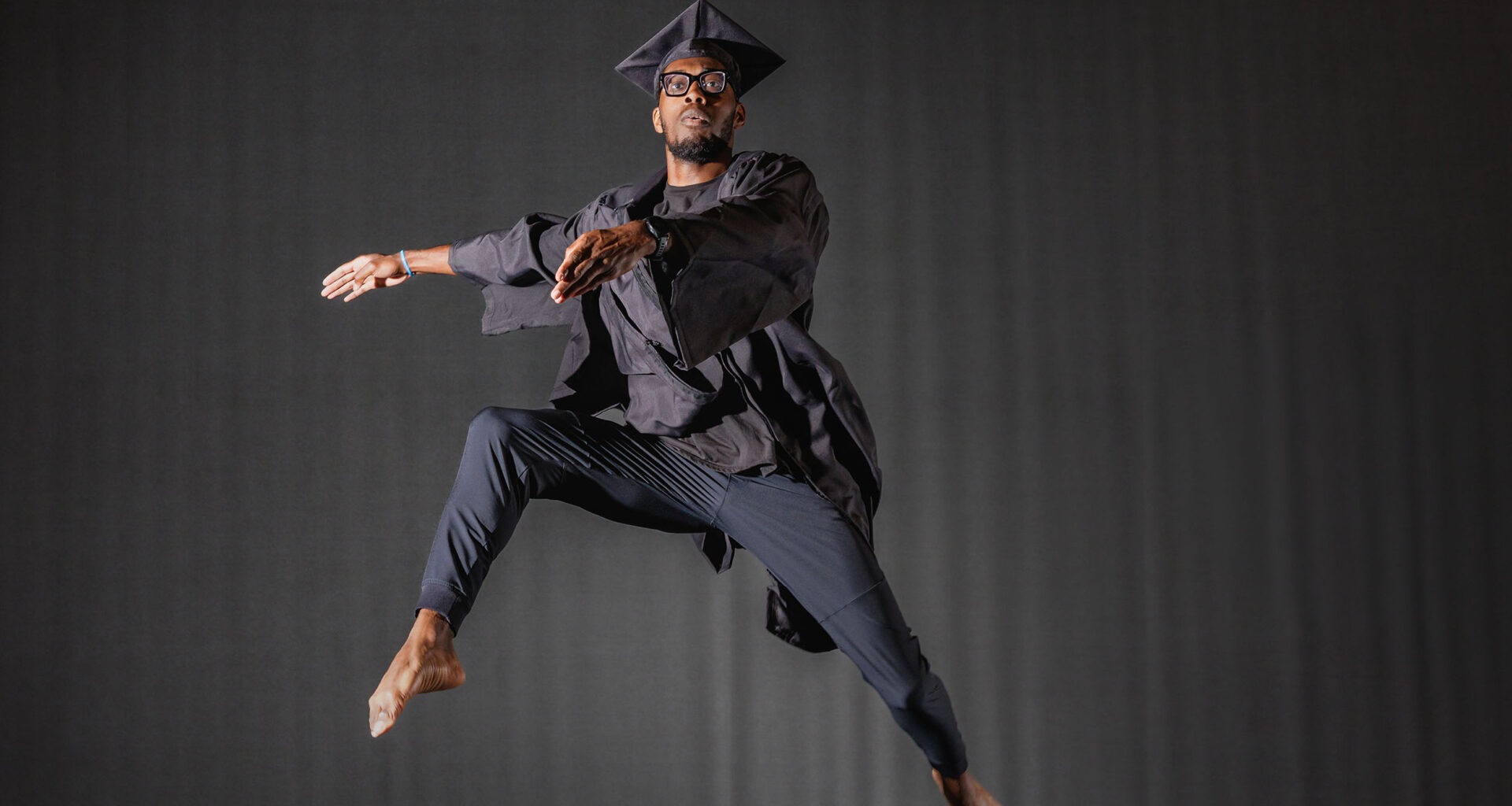 Portrait of Ephraim Bullock doing ballet in his graduation cap and gown