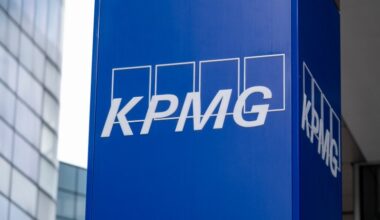 KPMG logo prominently displayed on a modern office building façade against a clear blue sky, symbolizing corporate presence