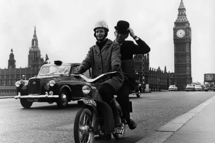 Moped navigating busy London street, highlighting urban transportation and city traffic dynamics