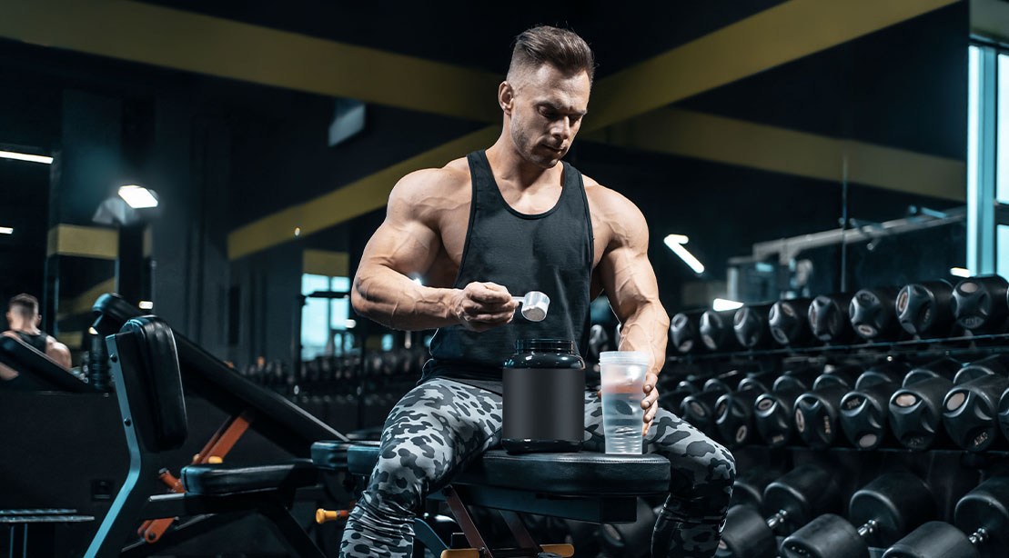 Muscular bodybuilder making a protein shake after his workout during the anabolic window time frame