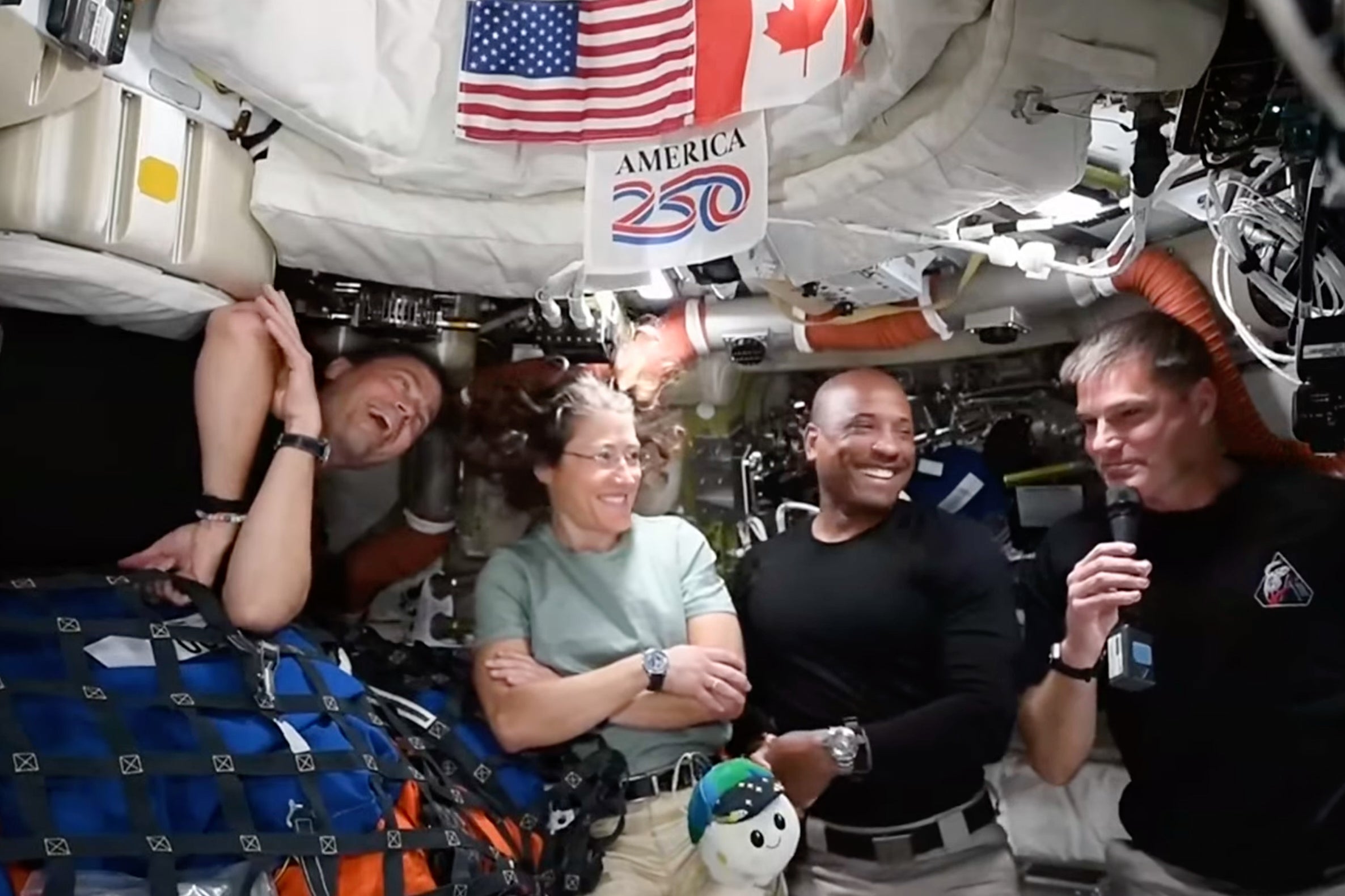 The Artemis II astronauts laugh together in an interview