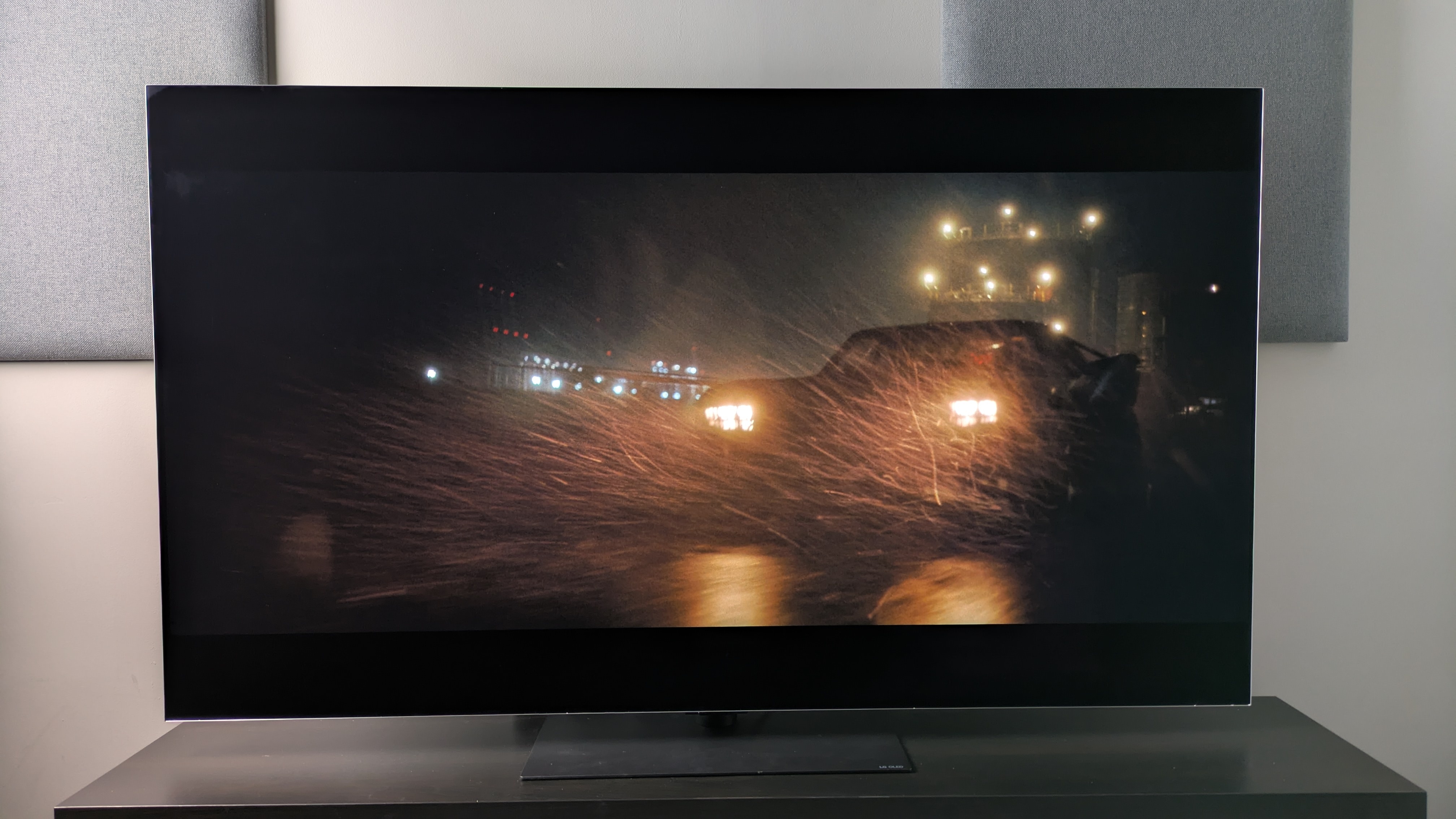 The LG G6 showing The Batman movie, with a short of the Batmobile racing down the street in the rain. Its bright headlights demonstrate strong contrast against deep black background tones