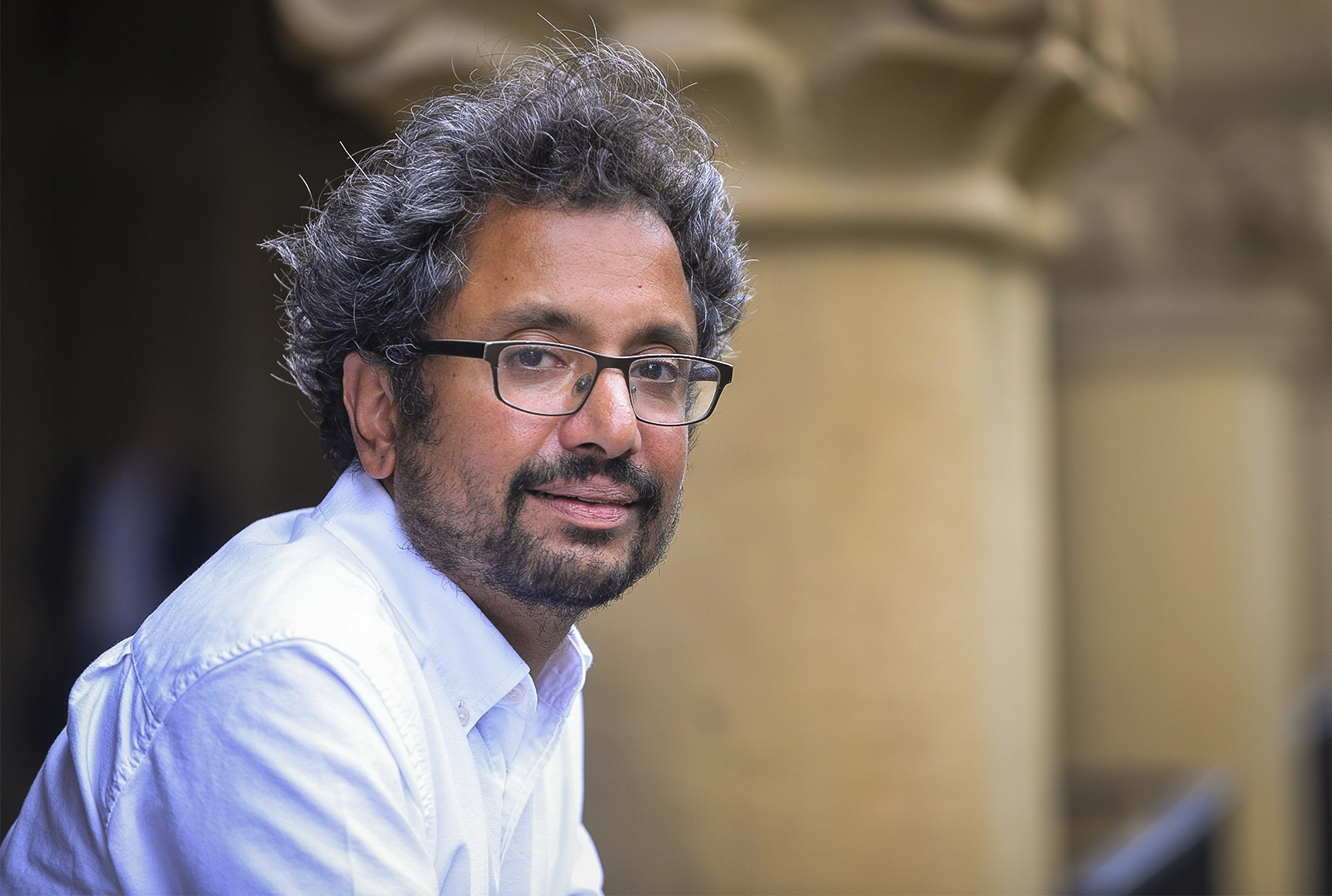 Man in glasses in front of a pillar.