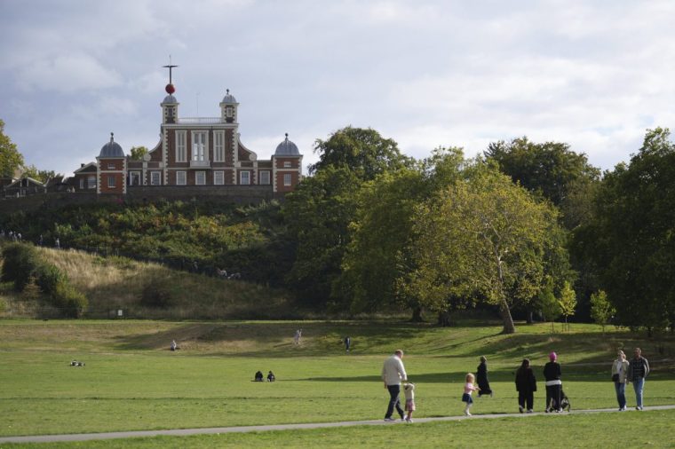 People walk in Greenwich Park in London, with the backdrop of the Royal Observatory, Monday, Sept. 22, 2025. (AP Photo/Joanna Chan)