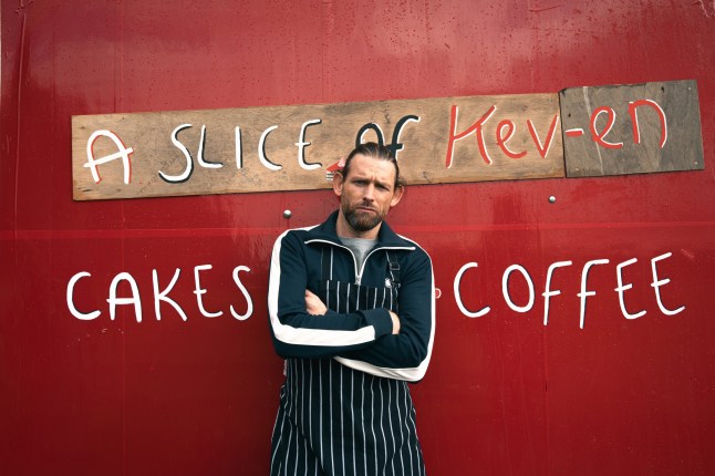 Emmerdale's Kev standing in front of a wall that says A Slice of Kev-end