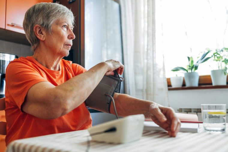 Senior woman self-monitoring blood pressure with a home device, managing health