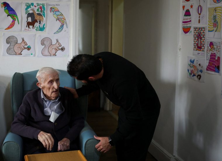 Deputy manager Kuldeep Singh speaks to an elderly resident at Applegarth Care Home, as the care sector braces for crisis over the British government's plans to reduce migration numbers, in Maidenhead, Britain, March 11, 2026. REUTERS/Isabel Infantes