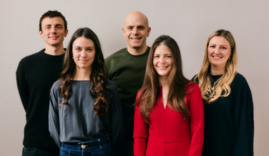 Five people stand together smiling at the camera