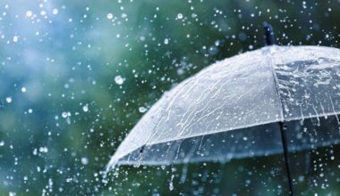 Transparent umbrella under heavy rain against water drops splash background.
