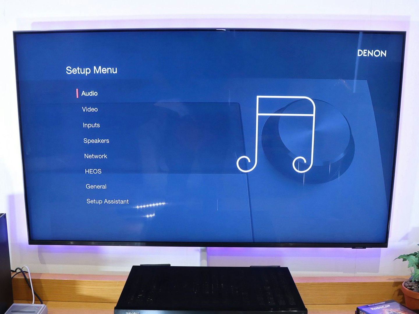 Denon AVR-X2800H Home Cinema Amplifier on a stand in a living room - tv showing setup menu