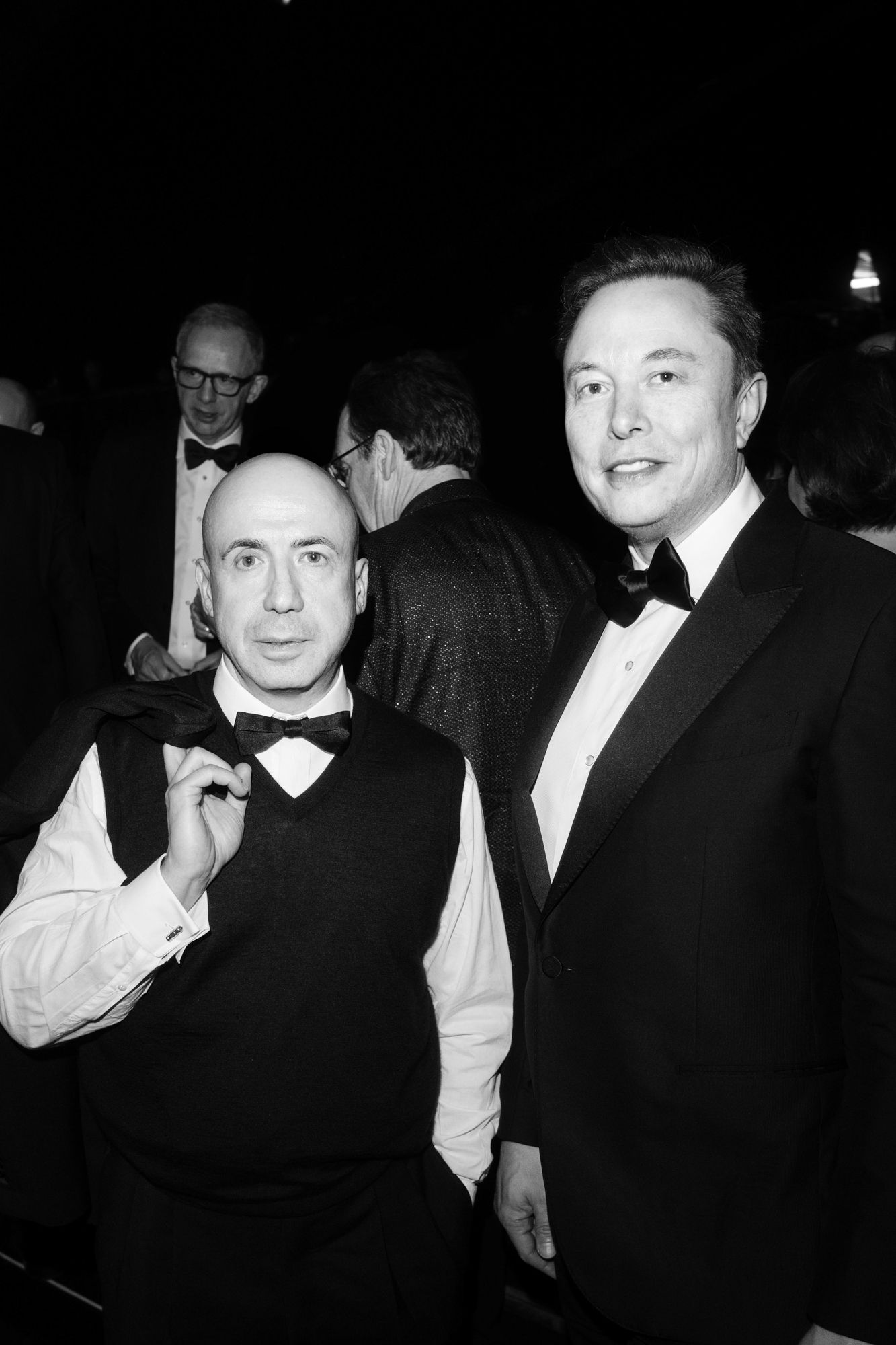 Image may contain Elon Musk Yuri Milner Willis Van Devanter Clothing Formal Wear Suit Tuxedo Accessories and Tie