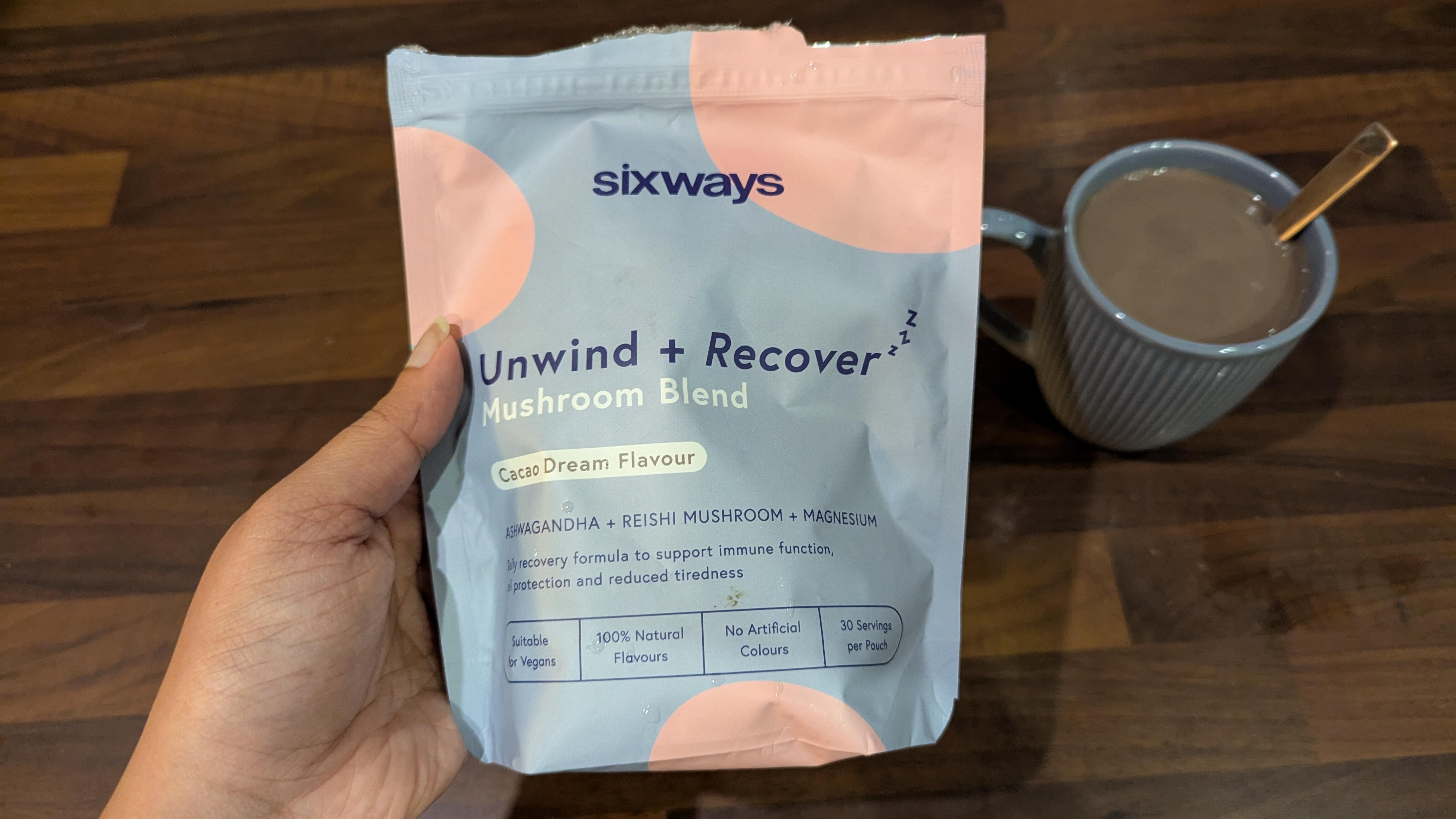 A pack of the Sixways Unwind+Recover Mushroom hot chocolate blend pack next to a cup of hot chocolate