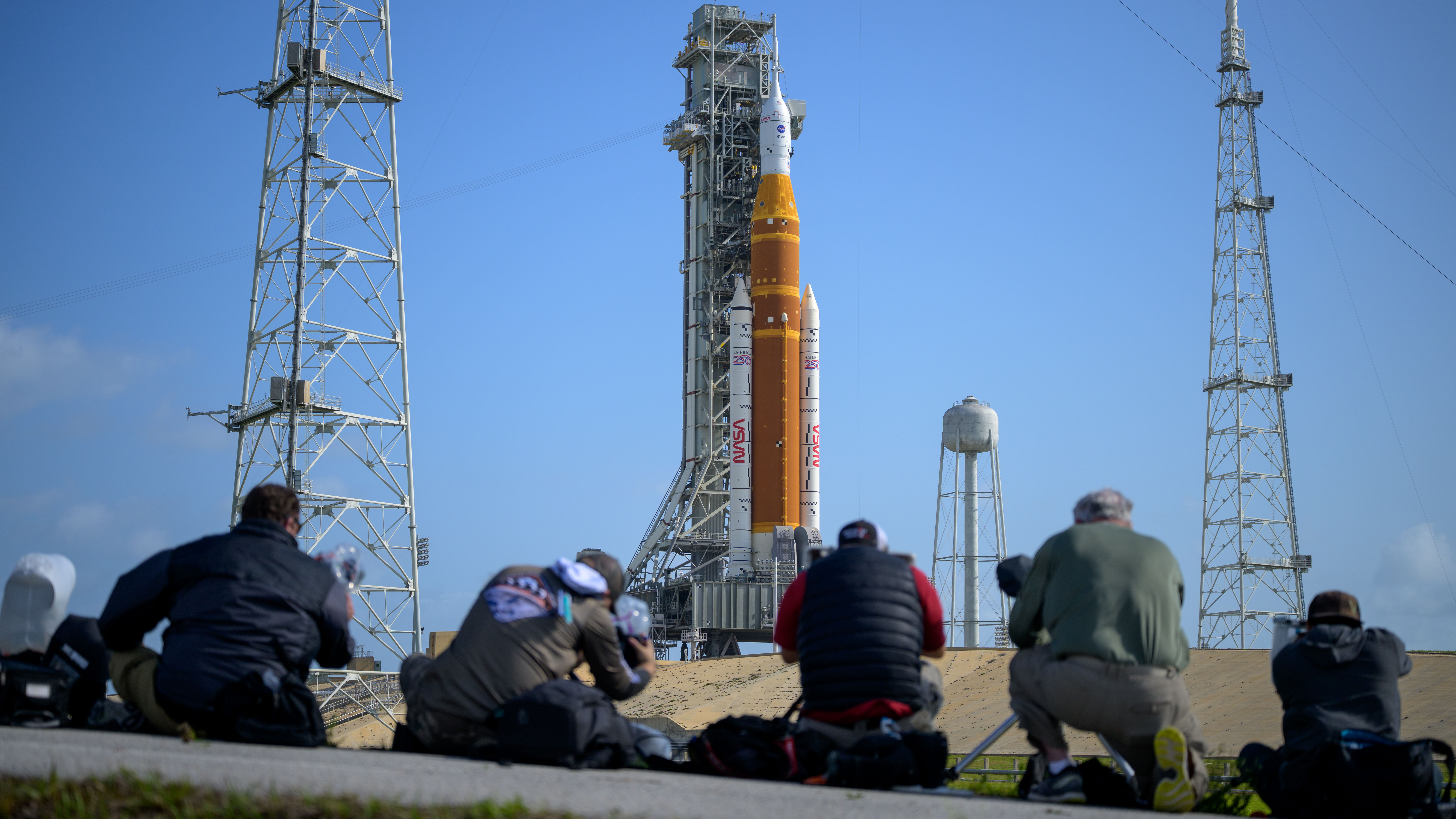 Media aim their remote cameras on NASA&rsquo;s Artemis II Space Launch System (SLS) rocket and Orion spacecraft, atop a mobile launcher at Launch Complex 39B, Sunday, March 29, 2026, at NASA&rsquo;s Kennedy Space Center in Florida. NASA&rsquo;s Artemis II test flight will take Commander Reid Wiseman, Pilot Victor Glover, and Mission Specialist Christina Koch from NASA, and Mission Specialist Jeremy Hansen from the CSA (Canadian Space Agency), around the Moon and back to Earth with launch opportunities beginning in April 2026. Photo Credit: (NASA/Bill Ingalls)