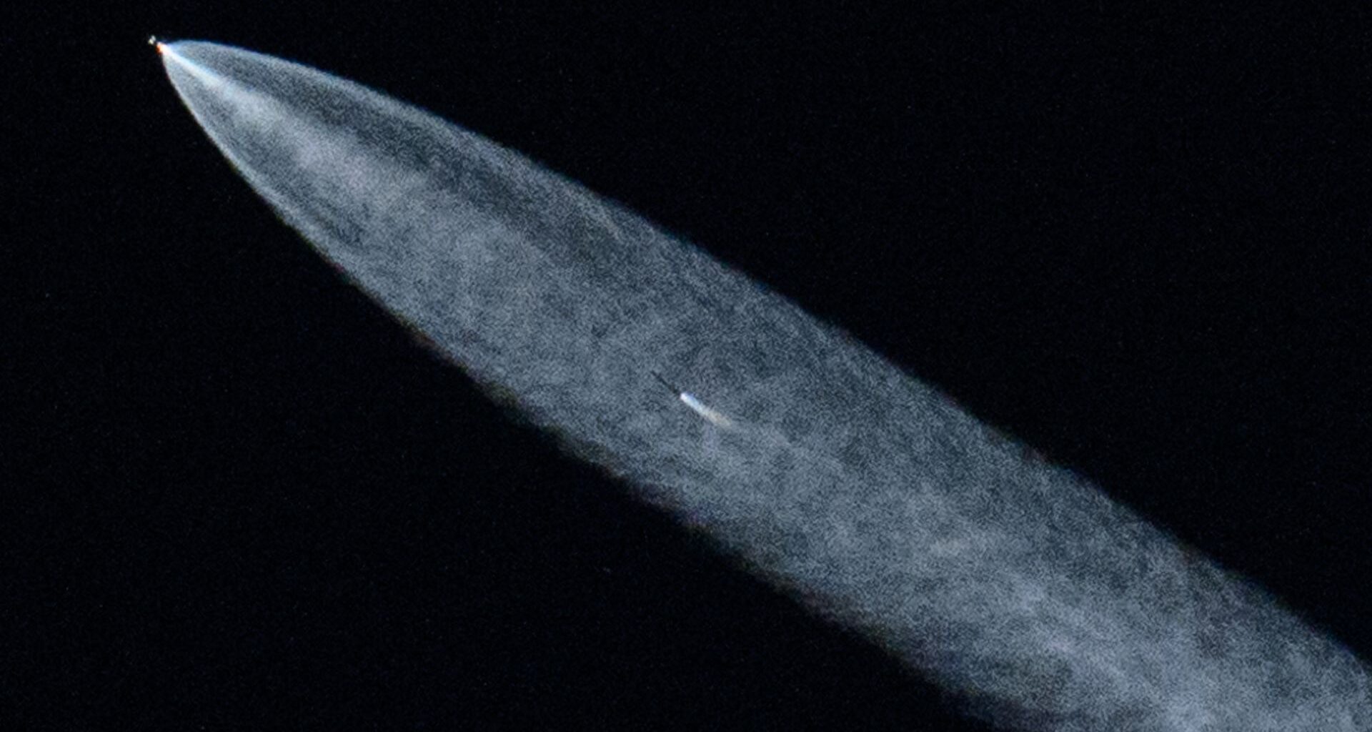 A streak of white shows a SpaceX rocket in the darkness of space.