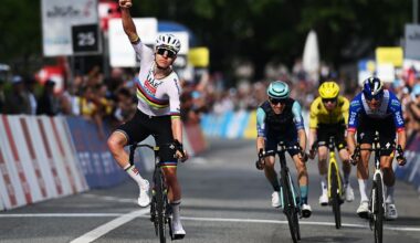 Tadej Pogacar raises his arm in celebration as three breakaway riders finish behind