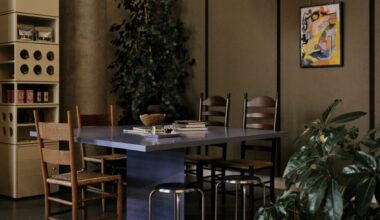 A home-looking coffee shop decorated with modernist furniture including spherical paper lanterns as lights, wood and chrome minimalist furniture, chrome table lamps, and thriving plants.