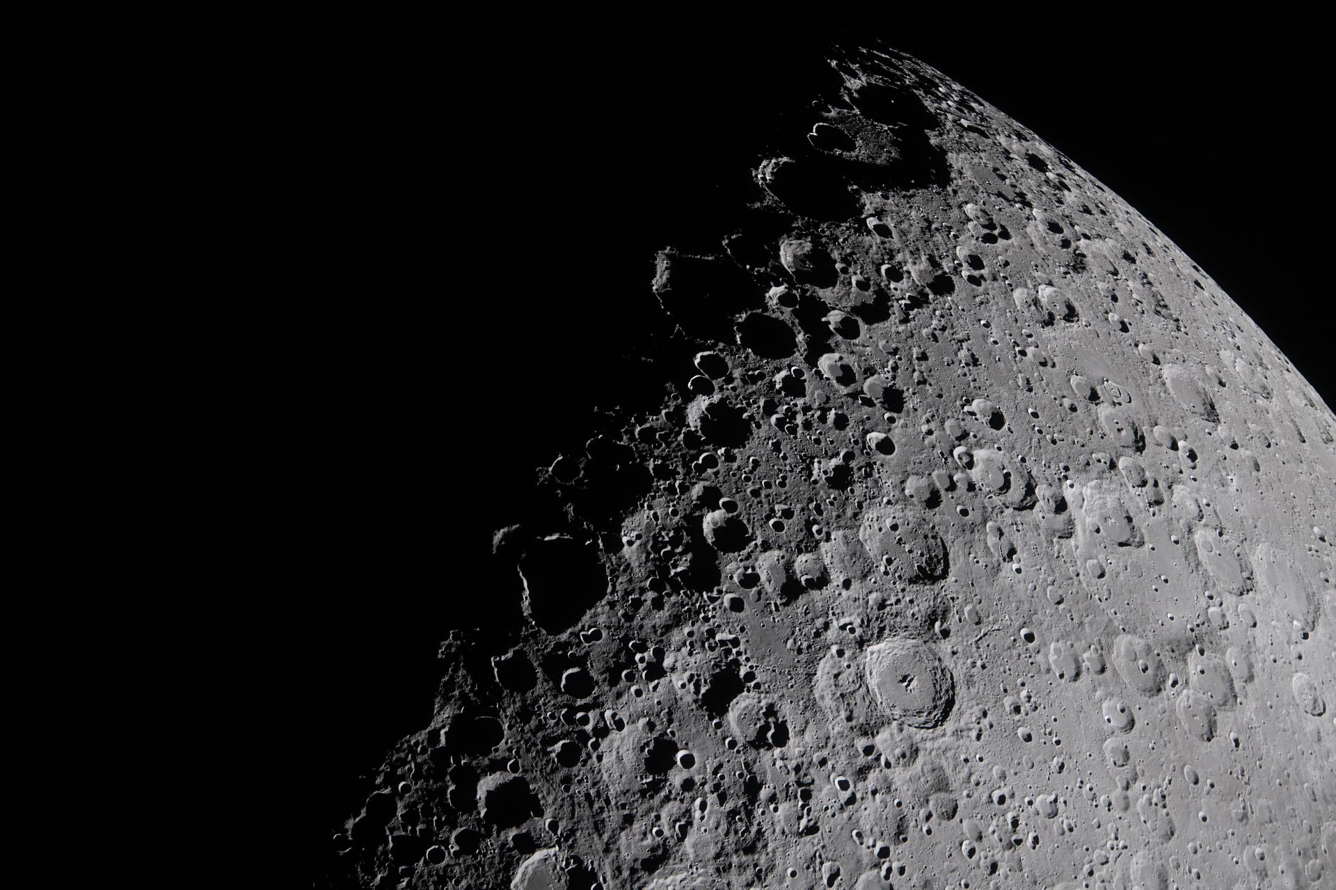 A portion of the Moon coming into view along the terminator – the boundary between lunar day and night – where low-angle sunlight casts long, dramatic shadows across the surface.