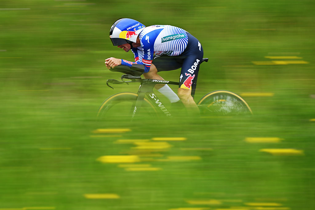 Primoz Roglic racing through out of focus green and yellow flora