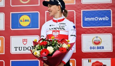 Kasia Niewiadoma-Phinney stands on the podium of Amstel Gold Race 2026, smiling to the side and holding a bunch of flowers in front of her