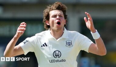 Henry Brookes, wearing a white Adidas cricket shirt with the Gloucestershire county logo, opens his mouth and puts his hands up by the side of his head after bowling a ball in the County Championship Division Two game against Lancashire