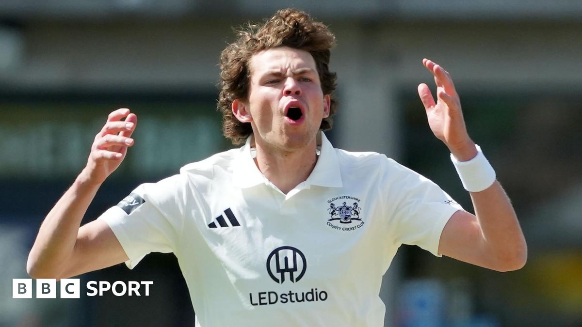 Henry Brookes, wearing a white Adidas cricket shirt with the Gloucestershire county logo, opens his mouth and puts his hands up by the side of his head after bowling a ball in the County Championship Division Two game against Lancashire