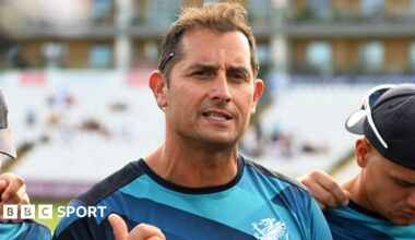 Jason Kerr, wearing a Somerset training top with navy blue, blue and light blue patterns and a white Somerset badge, while talking to his players before a T20 game against Glamorgan at the County Ground