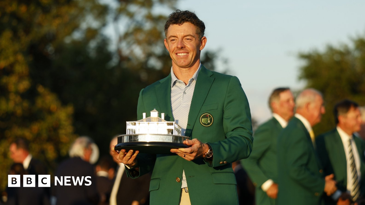 Rory McIlroy, a man wearing a green jacket and holding a silver trophy for winning the Masters in Augusta.