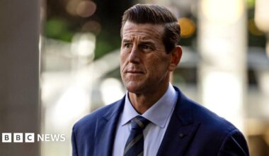 A front-on shot of Roberts-Smith looking pensively away from camera while wearing a suit and tie with strong background bokeh, as he walks along a street while arriving at the Federal Court in Sydney in May 2025.