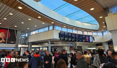 Crowds of passengers looking at boards in a train station.