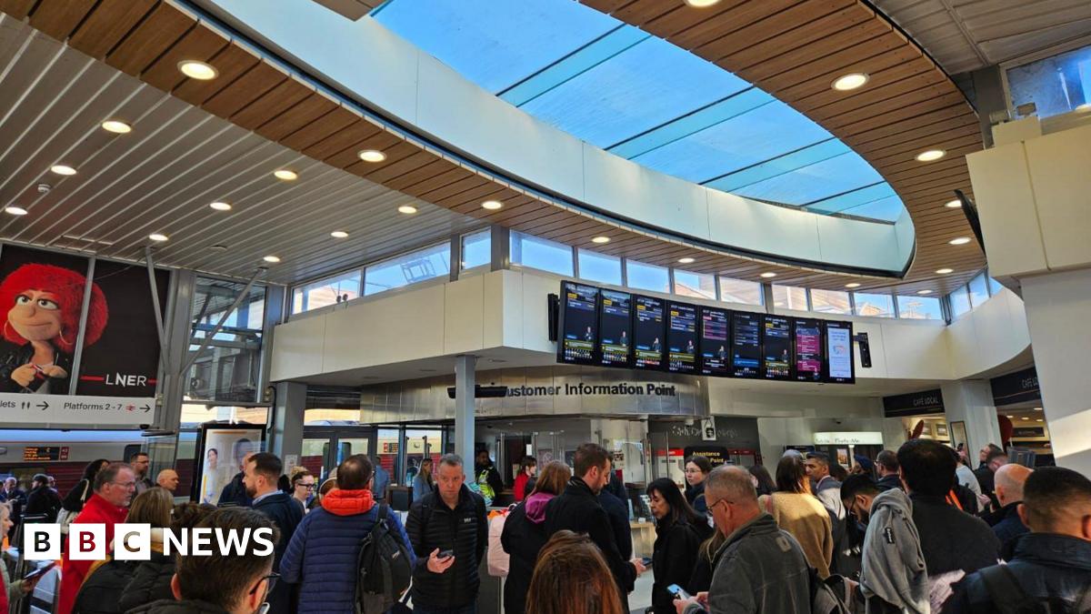 Crowds of passengers looking at boards in a train station.
