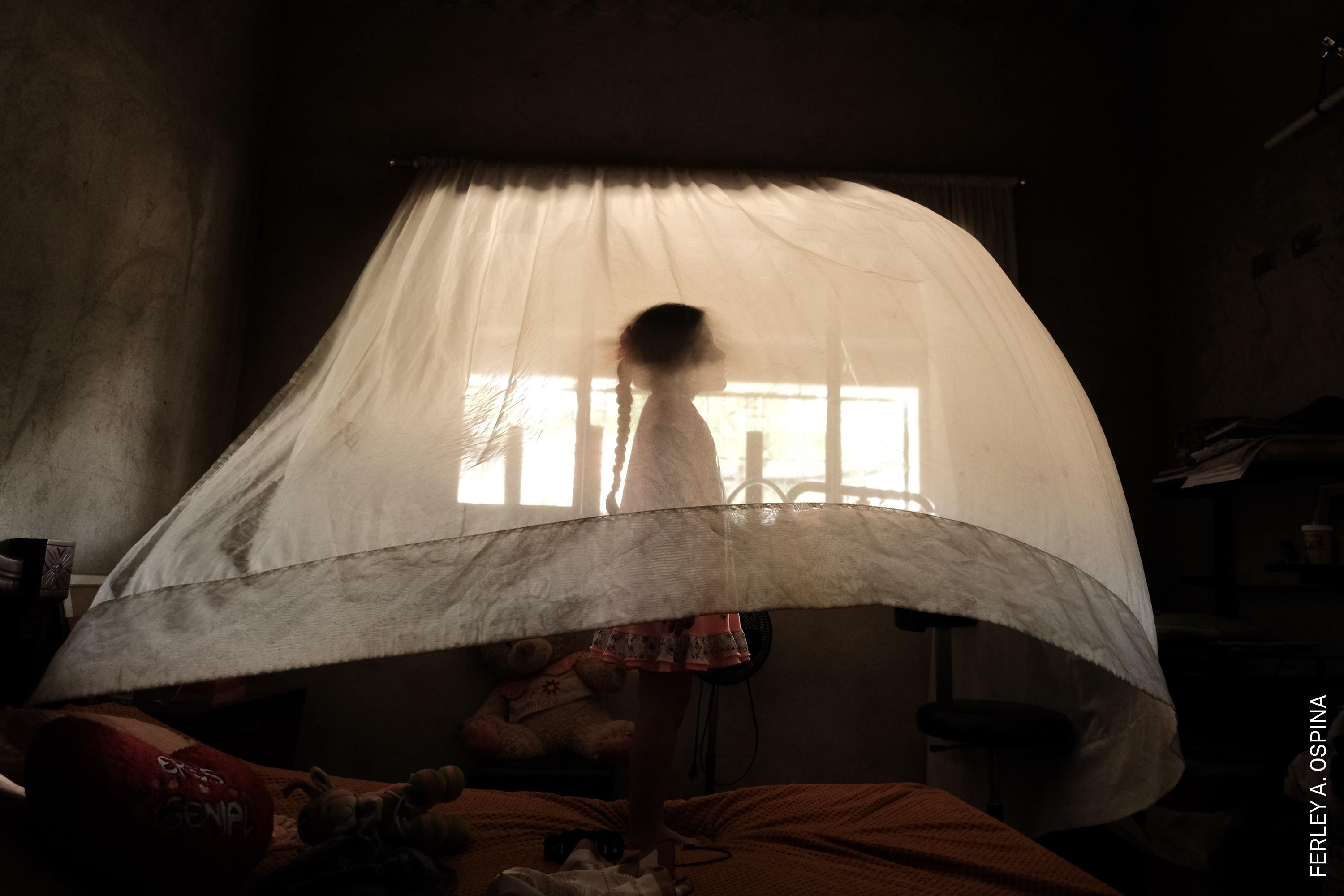 Valeria (5) plays behind a curtain at her aunt’s house. She is raised solely by her mother. In her region, 30% of households are headed exclusively by women