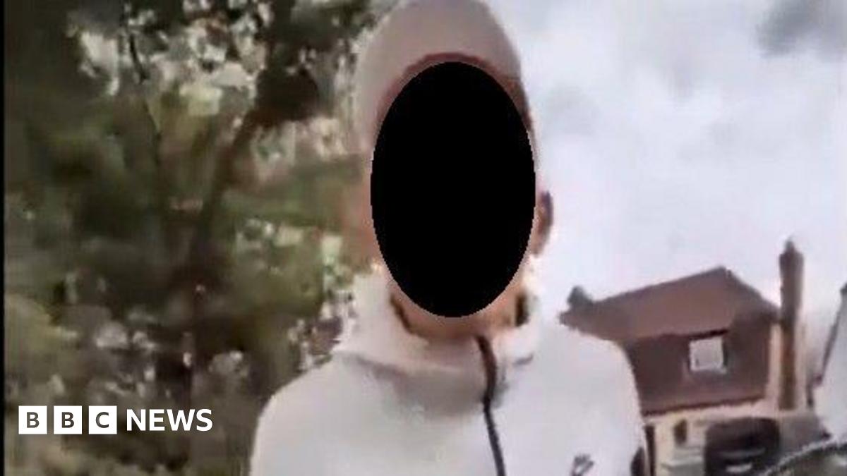 A man in a white, long-sleeved sports top and white cap is pictured facing the camera. Is face is obscured by a black circle.