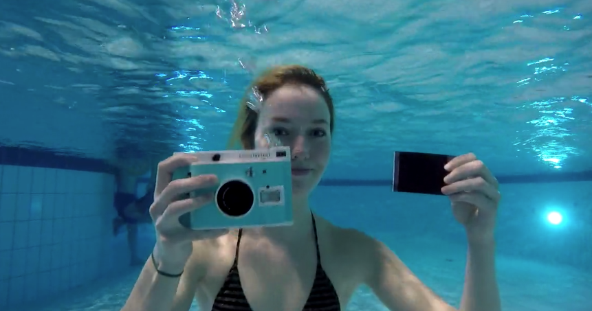 Underwater instant camera being held underwater by a female swimmer
