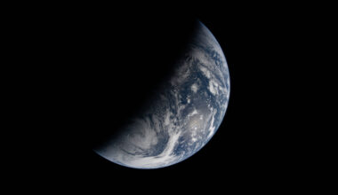 Image of Earth split by the terminator line. The terminator divides Earth’s surface diagonally, shrouding the top left half in darkness. Earth’s illuminated surface is mostly blue and covered in swirling white clouds.