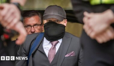 Former funeral director Robert Bush leaves Hull Crown Court, he is wearing a grey three piece suit with a purple tie and pocket square.