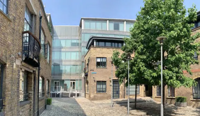 Cobblestone courtyard with brick buildings and a modern glass structure.