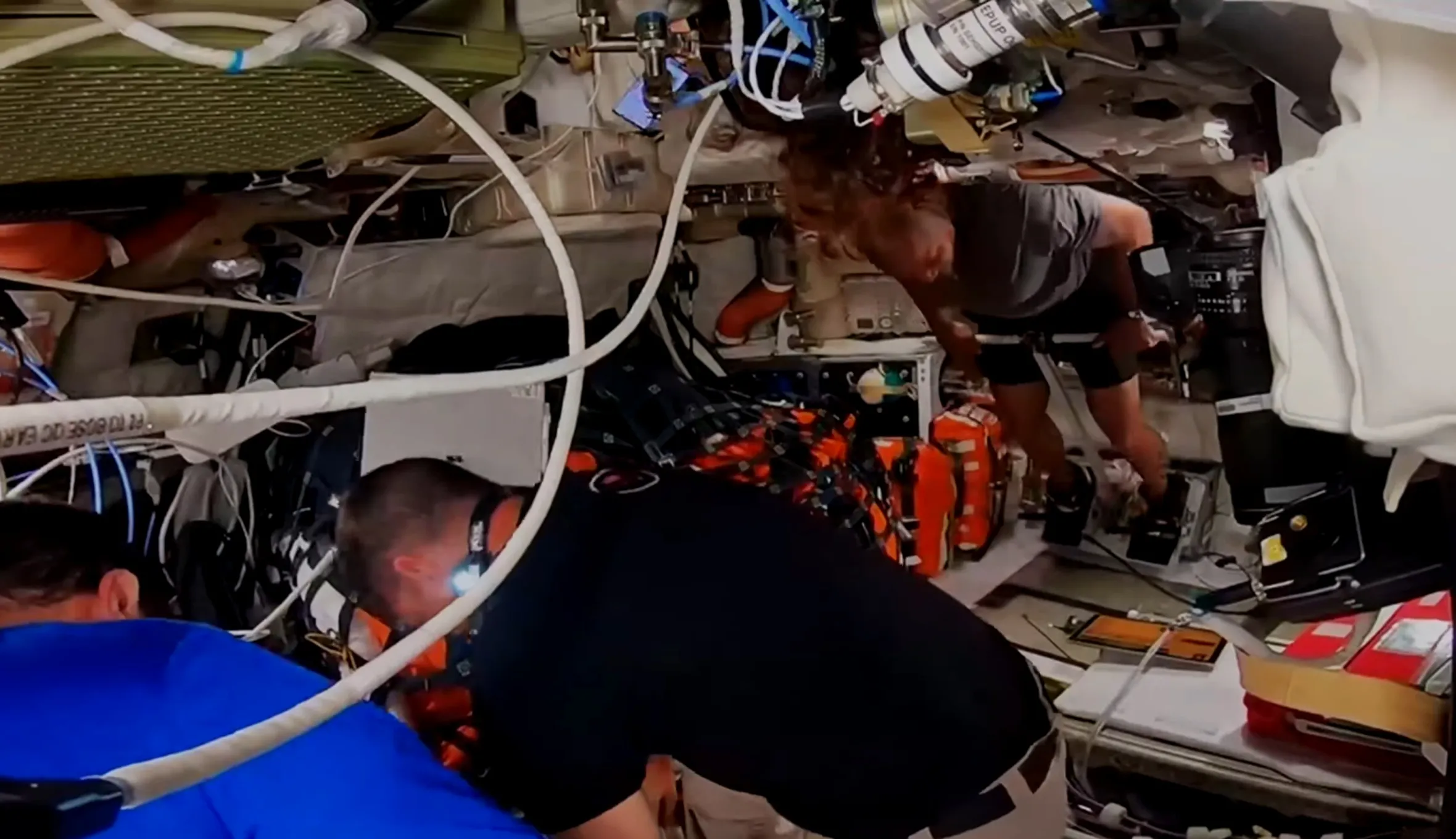 An astronaut exercising on equipment inside a spacecraft.