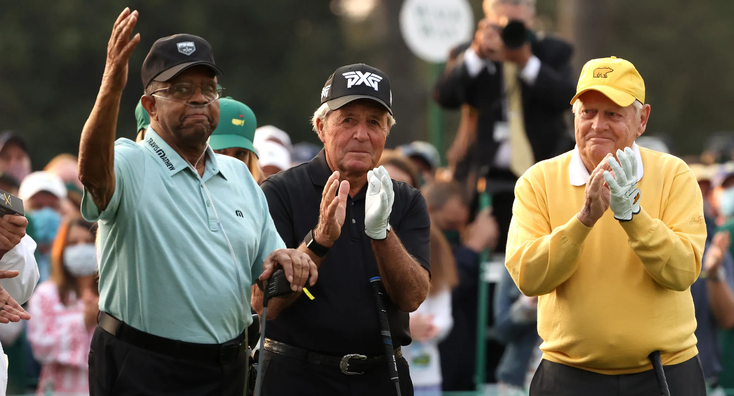 Honorary Starter Lee Elder waves as Gary Player and Jack Nicklaus applaud at the Masters opening ceremony.