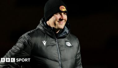 Departed Catalans Dragons head coach Joel Tomkins in club emblazoned hat and coat