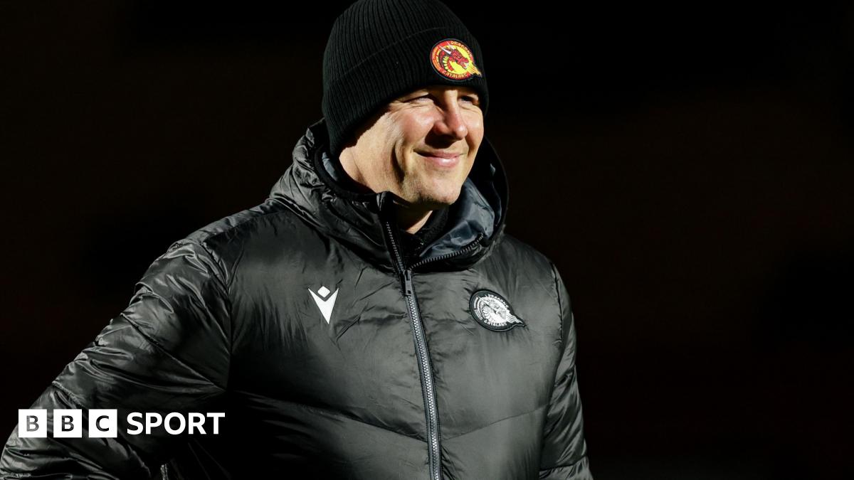 Departed Catalans Dragons head coach Joel Tomkins in club emblazoned hat and coat